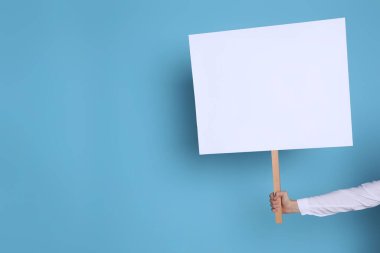Açık mavi arka planda boş tabela tutan kadın, yakın plan. Metin için boşluk