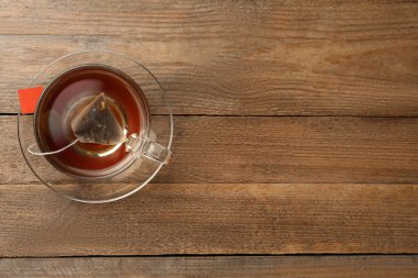 Cam bardakta çay poşeti, ahşap masanın üstünde sıcak su, üst manzara. Metin için boşluk