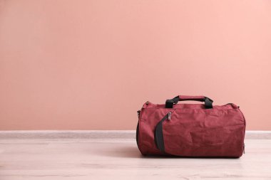 Pembe duvarın yanında yerde kırmızı spor çantası, mesaj için yer var.