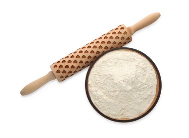 Beyaz zemin üzerinde un bulunan tahta merdane ve kase.