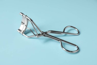 Açık mavi arka planda kirpik bigudisi. Makyaj aracı