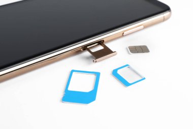 SIM kart ve cep telefonu beyaz masada, yakın plan.