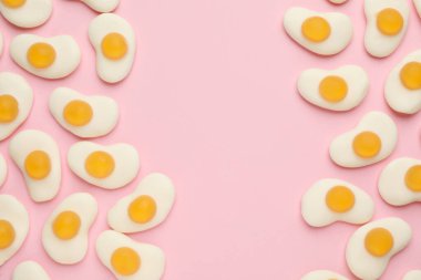 Pembe arka planda yumurta şeklinde leziz jöle şekerler, düz konum. Metin için boşluk