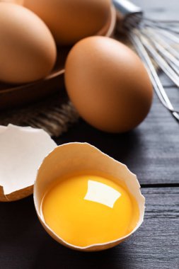 Koyu ahşap masada çiğ yumurta kabuğu ve çiğ yumurta sarısı.