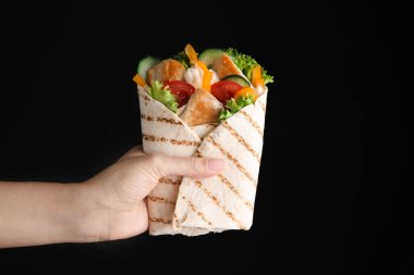 Siyah arka planda tavuk eti ve sebzeli lezzetli shawarmalar tutan kadın, yakın plan.