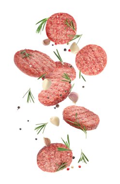 Beyaz arka plana dökülen taze çiğ hamburger köfteleri ve baharatlar. 