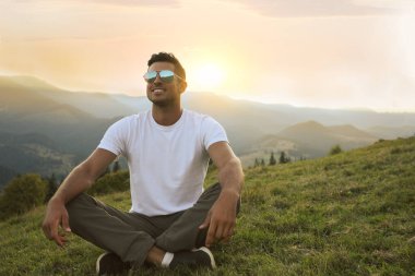 Yakışıklı adam gün batımında güzel dağ manzarasının tadını çıkarıyor.