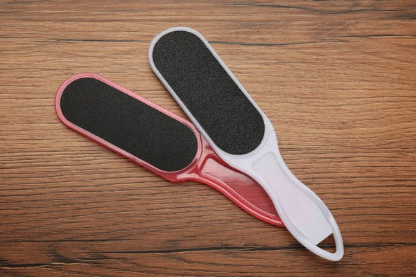 Colorful foot files on wooden table, flat lay. Pedicure tools