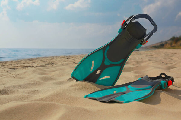 Пара бирюзовых ластов на песчаном пляже возле моря. Пространство для текста