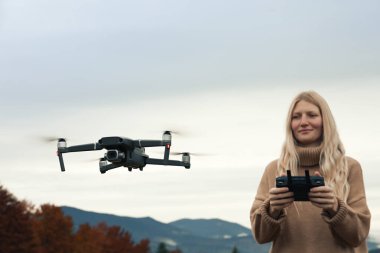 Genç kadın dağlarda uzaktan kumandalı modern drone kullanıyor.