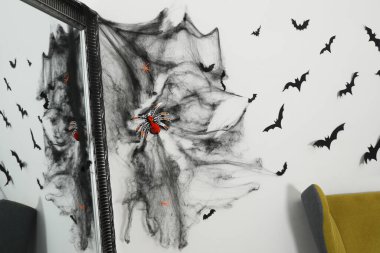 Kapalı alandaki ışık duvarının yanında örümcek ağı ve örümcek ağı olan ayna. Cadılar Bayramı Dekorasyonu