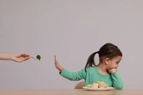 Linda Niña Negándose Comer Verduras Mesa Sobre Fondo Gris — Foto de Stock