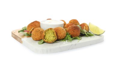 Beyaz arka planda otlu, limonlu ve soslu nefis falafel topları.