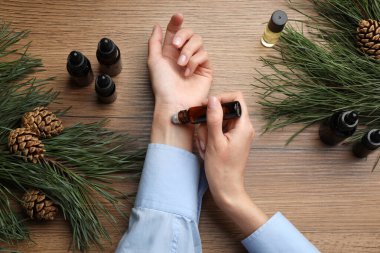 Kadın, ahşap masada bileğine çam yağı sürüyor.