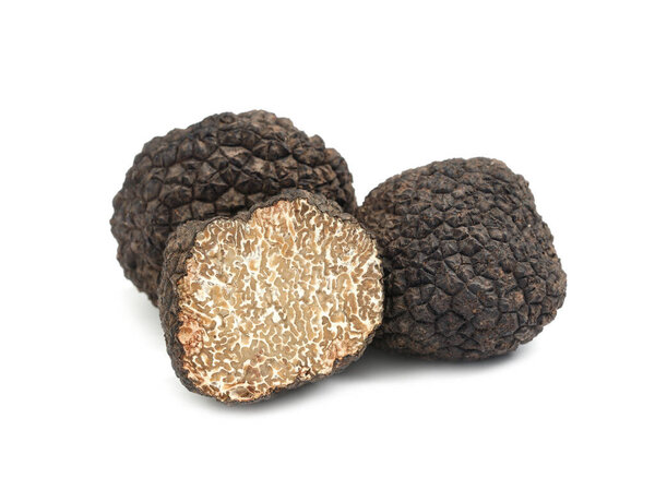 Cut and whole black truffles isolated on white