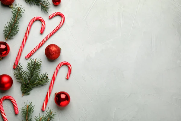 おいしいキャンディーの杖 モミの枝 灰色のテーブル 平らなレイアウトのクリスマスの装飾 テキストのスペース — ストック写真
