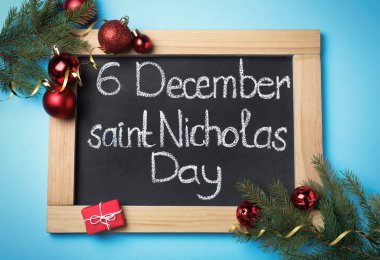 6 Aralık Saint Nicholas Günü yazılı küçük karatahta ve açık mavi zemin üzerine şenlikli dekor, düz yatıyordu