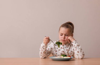 Gri arka planda yemek yemeyi reddeden tatlı küçük kız, mesaj atmak için yer var.