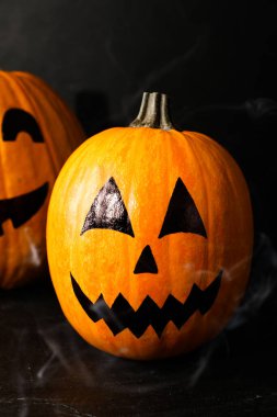 Karanlık arka planda çizilmiş ürkütücü yüzleri olan balkabakları. Cadılar Bayramı