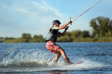 Genç çocuk nehirde wakeboard yapıyor. Aşırı su sporu