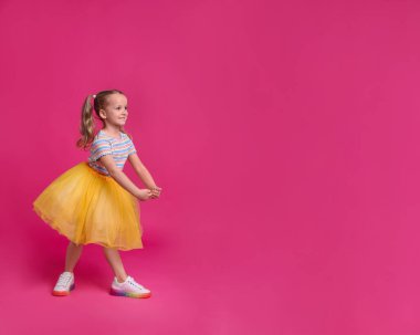 Tutu etekli şirin kız pembe arka planda dans ediyor. Metin için boşluk