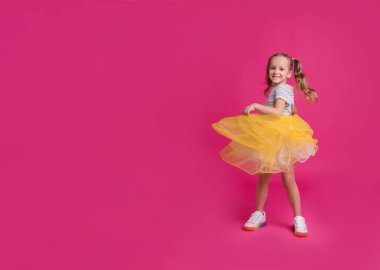 Tutu etekli şirin kız pembe arka planda dans ediyor. Metin için boşluk
