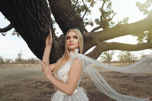 美丽的姑娘穿着仙女的衣服站在一棵大树前 — 图库照片