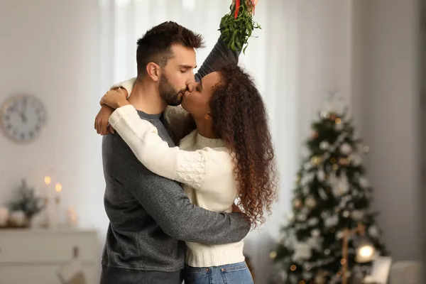 ハッピーカップル接吻の下にMisletoe束で部屋装飾されたクリスマス — ストック写真