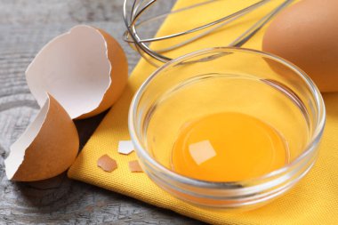 Gri ahşap masada çiğ yumurta sarısı olan kase, yakın plan.