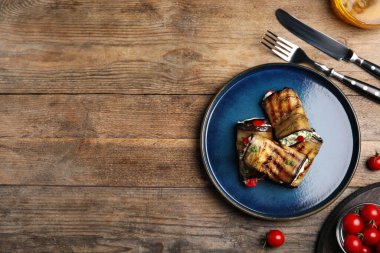 Ahşap masada servis edilen nefis fırınlanmış patlıcan ruloları. Metin için boşluk