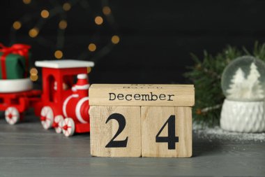 24 Aralık - Noel arifesi. Tahta blok takvimi ve masa üzerindeki dekorasyon bulanık festival ışıklarına karşı