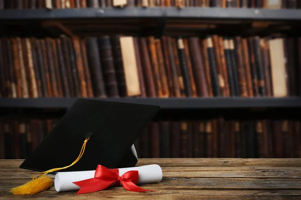 Καπέλο Αποφοίτησης Και Δίπλωμα Ξύλινο Τραπέζι Στη Βιβλιοθήκη Χώρος Για — Φωτογραφία Αρχείου