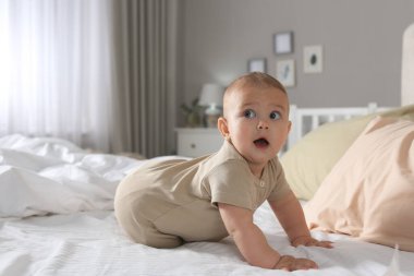 Evdeki yatakta emekleyen tatlı bebek.