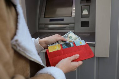 Dışarıdaki bankamatiğin yanındaki cüzdana para koyan kadın, yakın plan.