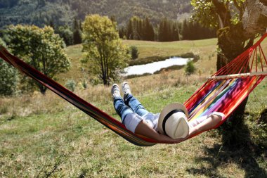 Güneşli bir günde hamakta dinlenen bir adam.