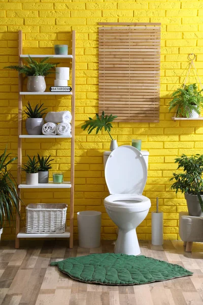 Стильная Ванная Комната Унитазом Зелеными Растениями Возле Желтой Кирпичной Стены — стоковое фото