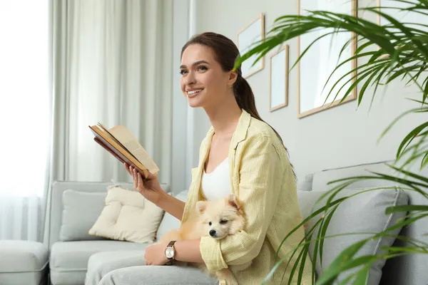 Gelukkig Jonge Vrouw Lezen Boek Met Schattige Hond Bank Woonkamer — Stockfoto
