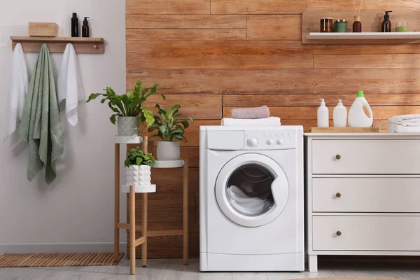 Laundry room interior with washing machine and stylish furniture
