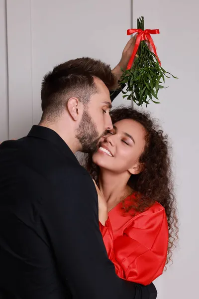 Homem Feliz Beijando Sua Namorada Sob Bando Visco Perto Parede — Fotografia de Stock