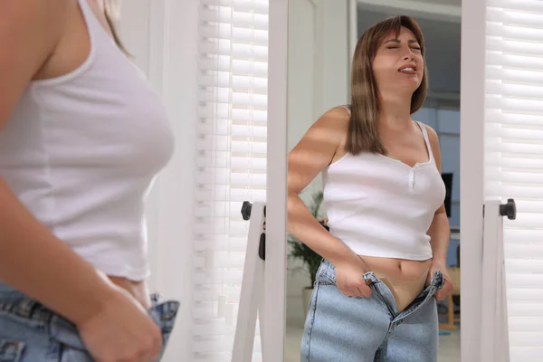 Ung Kvinna Kämpar För Att Sätta Tight Jeans Nära Spegeln — Stockfoto