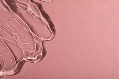Pembe arka planda şeffaf kozmetik jel, üst manzara. Metin için boşluk