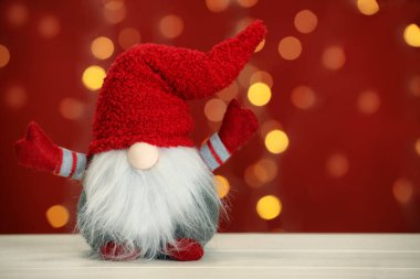 Beyaz ahşap masada bulanık festival ışıklarına karşı sevimli bir noel cücesi. Metin için boşluk