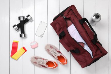 Spor çantası ve spor malzemeleri beyaz ahşap arka planda, düz yerde.