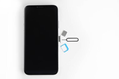 SIM kart, cep telefonu ve fırlatıcı beyaz masada, düz konum