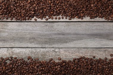 Ahşap masada kavrulmuş kahve çekirdekleri, düz uzanmış. Metin için boşluk