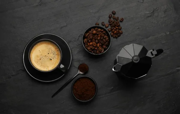 Flat lay composition with coffee grounds and roasted beans on black background