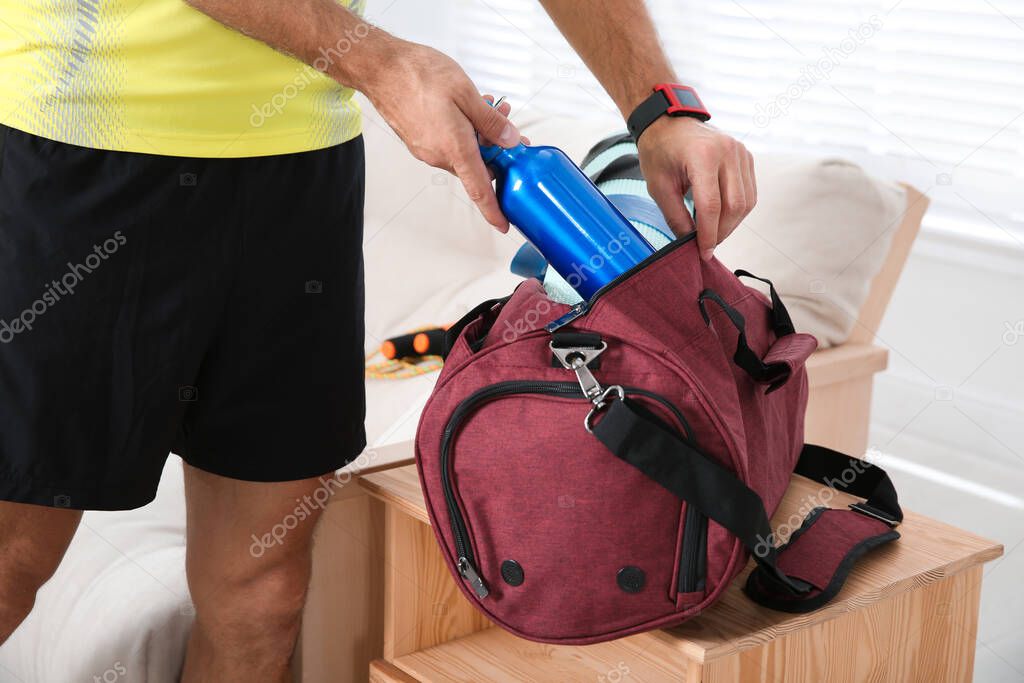 Man packing sports stuff for training into bag at home, closeup