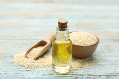 Açık mavi ahşap masada taze susam yağı ve tohumlar, yakın plan.