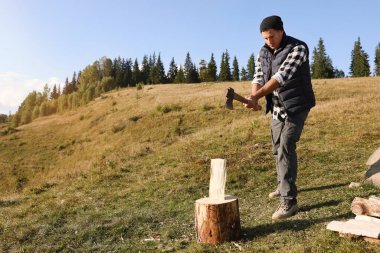 Tepede yakacak odun kesen baltalı yakışıklı adam.