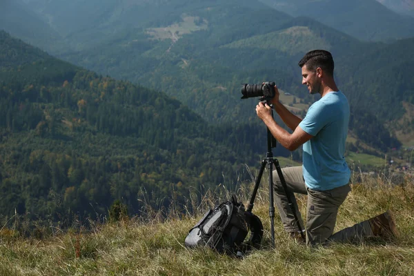 三脚の上で現代的なカメラで山の風景の写真を撮る男屋外 — ストック写真